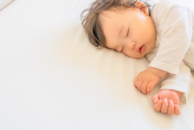 白いシーツの上ですやすや眠る赤ちゃん
