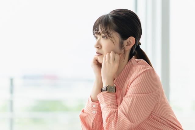 頬杖をついて考えごとをする女性
