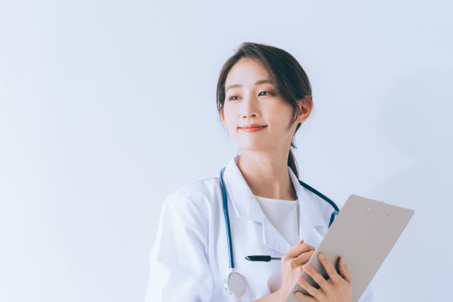 クリップボードを持ってほほえむ白衣の女性医師
