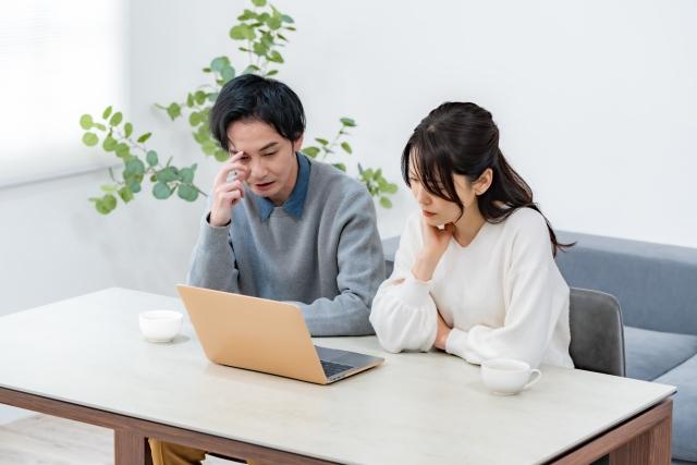 パソコンで情報を調べるカップル